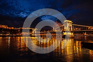 Night View Of Szechenyi Bridge. Famous Chain Bridge Of Budapest. Beautiful lighting and reflection in the Danube River.