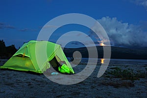 Night view of the tent near a mountain lake