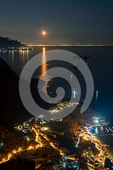 Night view from the top of the mountain to the Nerano bay. City lights. Coast of Amalfitana, Italy. Street houses and boats.