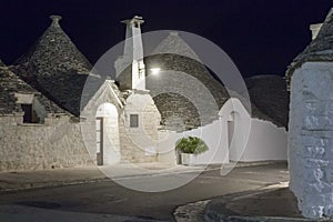Night view of a traditional narrow street in Alberobello, with its famous construction names