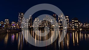 Night view of Vancouver skyline, Canada in downtown with lights of illuminated skyscrapers reflected in the calm water.