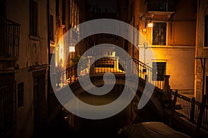 Night view of Venice with a small bridge in the yellow light of lanterns