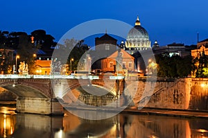 Night view of Victor Emmanuel bridge over Tiber river with St. Peter`s Cathedral dome at background, Rome, Italy