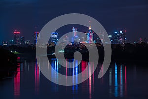 Night view on the Warsaw city buildings with lights reflection in the river.