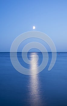 At night a white moon over the sea with a reflection and a path