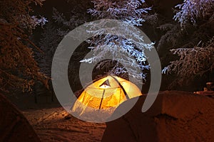 Night winter camp with tents in snowy forest