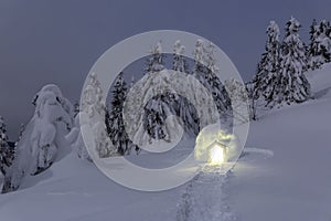 Night winter mountain landscapes. Igloo stands on the snowy lawn. House with light. Location place the Carpathian mountains.