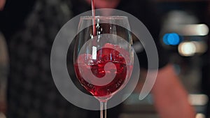 In a nightclub or pub a bartender preparing a cocktail with ice and Wine. Red wine flows into the glass. Slow-Mo