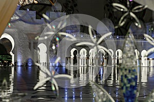 The nights view through a decorative glass door of inner courtyard of Sheikh Zayed Grand Mosque in Abu Dhabi city, United Arab