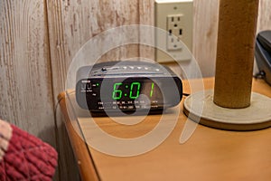 A nightstand with a tabletop lamp, alarmclock, and touchtone phone