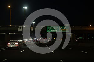 Nighttime highway with vehicles in motion illuminated by streetlights - directional signs for Steeles Ave and Woodbine Avenue photo