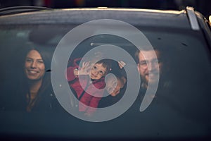 In the nighttime hours, a happy family enjoys playful moments together inside a car as they journey on a nocturnal road