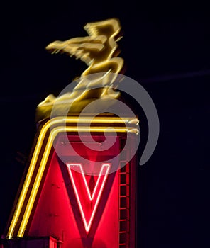 A nighttime image of a neon sculpture portrays a speeding individual