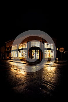 Nighttime shot of hometown storefront with reflections in street.