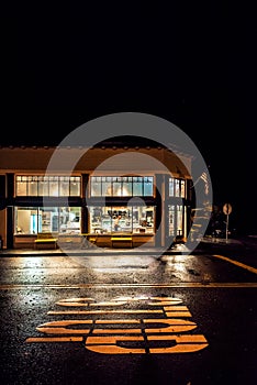 Nighttime shot of hometown storefront with reflections in street.