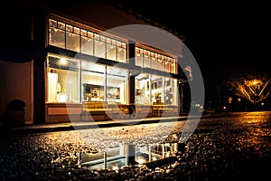 Nighttime shot of hometown storefront with reflections in street.