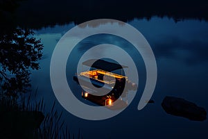 nighttime shot of litup pontoon boat floating on a tranquil lake