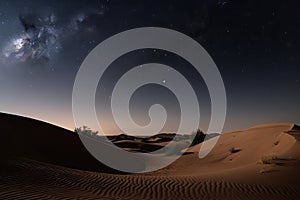 nighttime stars over the dunes of a desert, with crescent moon in view