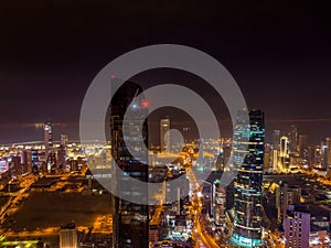 Nighttime view of a bustling city skyline, illuminated by the lights of buildings in Kuwait City
