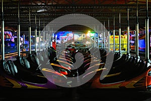 Nighttime view of two colourful rows of Dodgems facing each other.