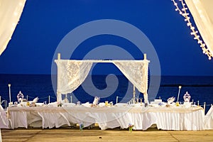 this nighttime wedding reception is illuminated by christmas lights and is by the beach