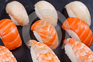 Nigiri sushi with salmon,grouper and prawn, served on black ston