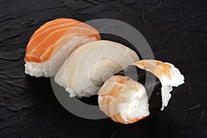 Nigiri sushi set, close-up on a black background. Fresh salmon, white fish, and shrimp