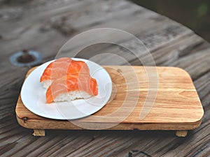 Nigiri Sushi in white dish on the wooden tray and wooden background with natural light.