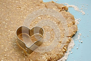 Heart-shaped cookie cutter on raw organic dough