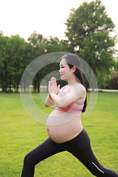 Asian Eastern Chinese young pretty pregnant girl woman do yoga stand in meditation, do lotus gesture of yoga outdoor nature sunset