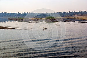 Nile river with the banks full of trees and vegetation and Egyptian fishermen in their typical rowing boats in the center of the r