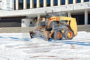 Nimble grader cleans the area from snow on a clear winter day