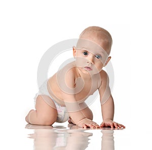 Nine month old infant baby boy with blue eyes wearing diaper crawling