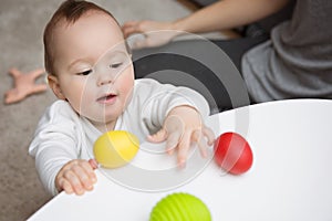 Nine months old baby girl trying to grab colorful toy eggs