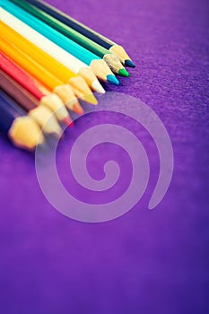 Nine multicolored pencils on a purple felt background. Different colored pencils with space for text. Back to school. Art lessons