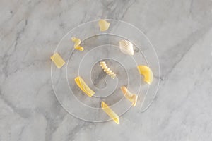 Nine types of different pasta rest on a marble table with copy space for your text
