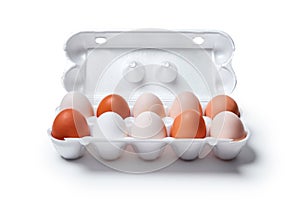 Egg crate with nine white eggs and one brown isolated on a white background