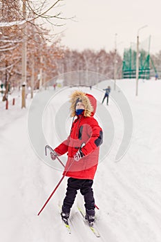Nine-year-old boy walks through the forest on cross-country skis