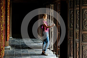 Ninh Binh / Vietnam, 08/11/2017: Woman standing in a traditional wooden doorway of a Buddhist temple in the Trang An grottoes