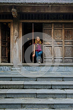 Ninh Binh / Vietnam, 08/11/2017: Woman standing in a traditional wooden doorway of a Buddhist temple in the Trang An grottoes