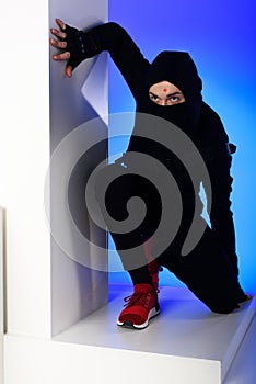 ninja in black clothing with katana behind standing on white block