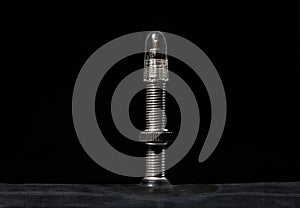 The nipple of a bicycle camera on a black, macro