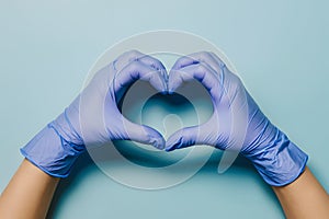 Nitrile gloves in heart shape against blue backdrop, symbolizing precision and care