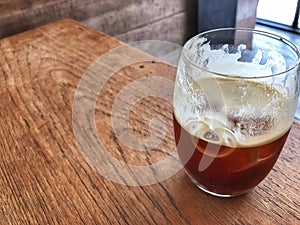 Nitro cold brew coffee glass on the wooden table with natural light