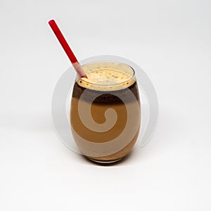 Nitrogen infused cold brew coffee with a red straw in a clear glass on a white background.