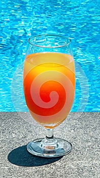 No alcohol, fruit cocktail sits by sparkling pool, evoking leisure and vacation vibes