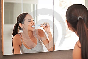 No bad breath for me. A beautiful young woman brushing her teeth in her bathroom.