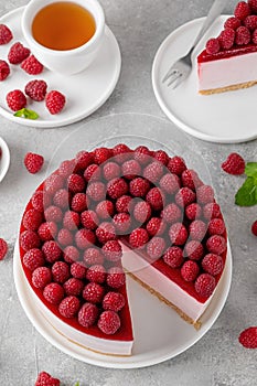 No baked raspberry cheesecake or raspberry cream mousse cake with jelly and fresh berries on top on a white plate