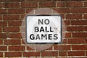 A No ball games sign on a brick wall on the side of a property