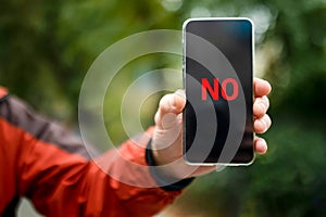 NO on the smartphone screen. A smartphone with the word NO on the smartphone screen in a man& x27;s hand. Message using a